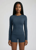 Woman wearing a teal long-sleeve top and shorts on a light gray background